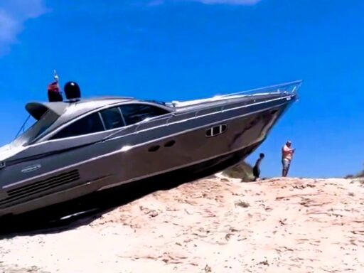 A 59-foot Pershing 54 luxury boat marooned on S'Espalmador after crashing, leaving its bow dangling. Rescue services responded, but crew members unharmed and managed the situation.